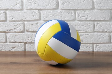 One volleyball ball on wooden surface against white brick wall