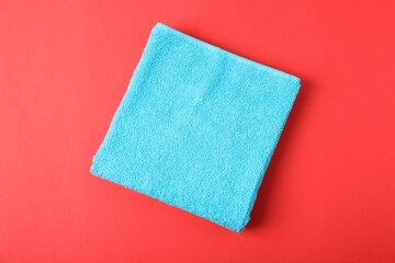 Light blue terry towel on red background, top view