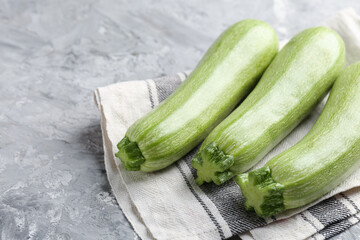 Fresh ripe zucchinis on grey textured table, closeup. Space for text