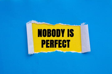 Nobody is Perfect message written on ripped torn blue paper on yellow background. Conceptual Nobody is Perfect symbol. Copy space.
