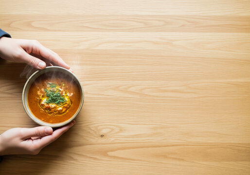A volunteer serving a warm bowl of soup at a shelter a concept of community support and fighting hunger with copy space on a plain table for a charity message