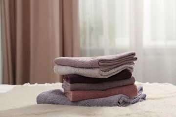 Stack of terry towels on bed indoors, closeup