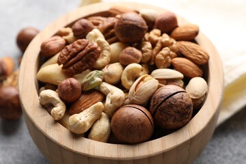 Mix of different nuts in bowl on grey table, closeup