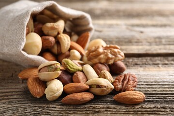 Mix of different nuts in bag on wooden table, closeup. Space for text