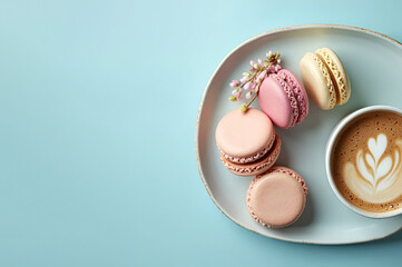 Multicolored French macarons on a plate, next to a cup of cappuccino with a pattern on a light blue background. Top view.