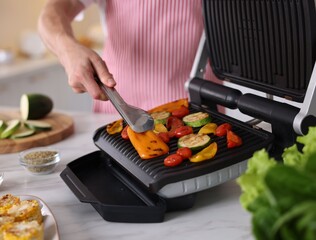 Man cooking vegetables on electric grill in kitchen, closeup