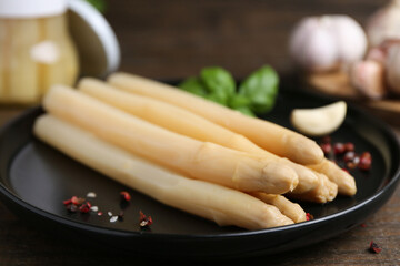 Pickled asparagus and spices on wooden table, closeup