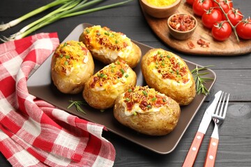 Tasty stuffed baked potatoes served on black wooden table, closeup
