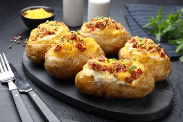 Tasty stuffed baked potatoes served on black table, closeup