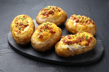 Tasty stuffed baked potatoes on black textured table, closeup