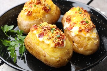Tasty stuffed baked potatoes in baking dish on table, closeup