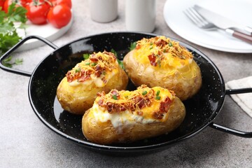 Tasty stuffed baked potatoes in baking dish served on grey table, closeup