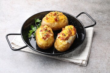 Tasty stuffed baked potatoes in baking dish on grey table