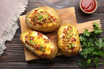 Tasty stuffed baked potatoes served on wooden table, flat lay