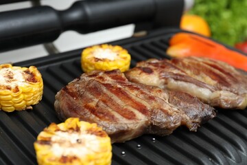 Electric grill with tasty meat and vegetables, closeup