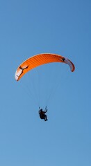 Paraglider flying in clear blue sky
