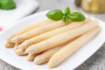 Pickled asparagus spears with basil on grey table, closeup