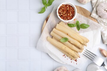 Pickled asparagus spears served on white tiled table, flat lay. Space for text