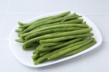 Fresh green bean pods on white tiled table, closeup