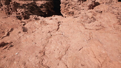 Exploring a vast canyon with rugged red rock surfaces, where nature reveals ancient formations shaped by time and weather. The sunlight casts shadows, highlighting the textures and colors around.