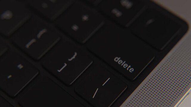 Close-up of delete key on modern black laptop keyboard, symbolizing erase, remove, data control, digital security, office work and technology detail