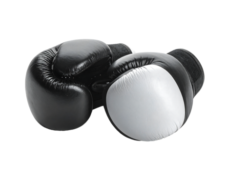 A pair of black and white leather boxing gloves, one flipped, rests on a black background