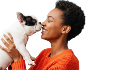 Young Afro-American woman in orange sweater holding white French Bulldog puppy, noses touching, both smiling in bright studio with blue background, concept of profound joy and love