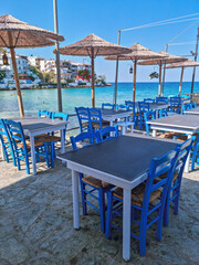 Blue Restaurant tables from a traditional Greek taverna overlooking the Mediterrenean sea with turqoise blue waters in the background, Skala Marion, Thassos island, Northern Greece
