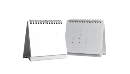 Two blank white desktop calendars, one with dates, sit angled on a surface.  Spiral bound