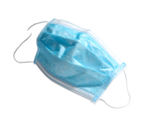 A light-blue, disposable face mask with ear loops, slightly crumpled, lies on a black background