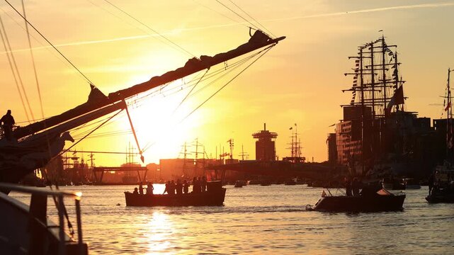 boats and tall ship with tourists cruising on golden IJ river with tall ships in the background at sunset during Sail Amsterdam 2025