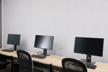 Fototapeta premium Open office interior. Modern workplaces with computers near light grey wall