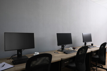 Open office interior. Modern workplaces with computers near light grey wall