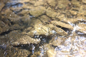 Many stones under flowing clean water, closeup