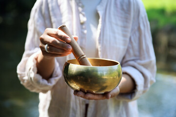 Woman with singing bowl in nature, closeup