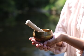 Woman with singing bowl in nature, closeup