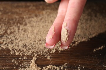 Woman showing dust from top of wooden table, closeup