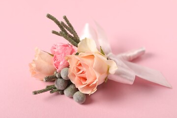 Boutonniere with beautiful flowers on light pink background, closeup