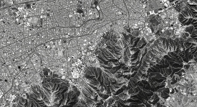 Photo of aerial view of a sprawling city nestled against rugged, mountainous terrain, showcasing urban development and natural landscapes