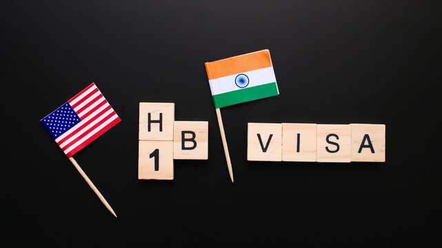 H1B VISA spelled with wooden letter with USA and India flags on black background