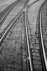 Obraz premium Rails of the famous historic tram in Porto (Portugal). Switches and tracks in a curve at the terminus in the old town. Black-and-white infrastructure background with cobblestones. 