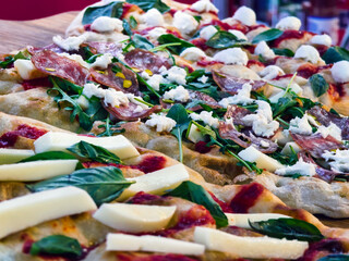 Delicious fresh pizza topped with salami, spinach, and cheese served at a bustling restaurant in the afternoon