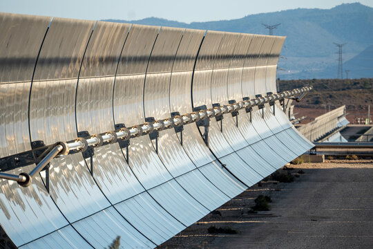 Solar thermal power station with rows of parabolic trough mirrors reflecting sunlight. Renewable energy facility showcases cutting-edge technology for sustainable electricity generation.