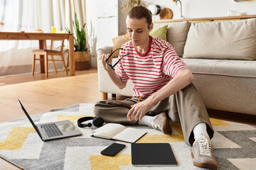 Young handsome man relaxes on the floor, lost in thoughts while working on creative ideas
