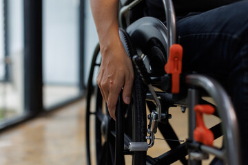 diseased man is sitting in a wheelchair, He holds his hands on the wheel wheelchair Recovery and healthcare concepts.
