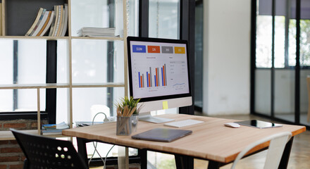 Desktop Computer Monitor with Finance Statistical Data a white-screen mockup for display your graphic is on a white desk in a modern bright living room.

