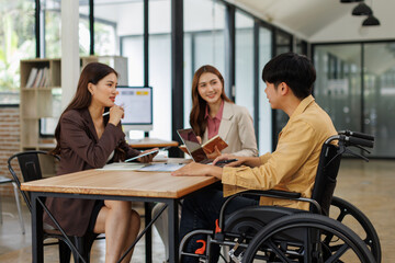 An inclusive modern office environment with a diverse team collaborating. A person in a wheelchair actively engages with colleagues.
