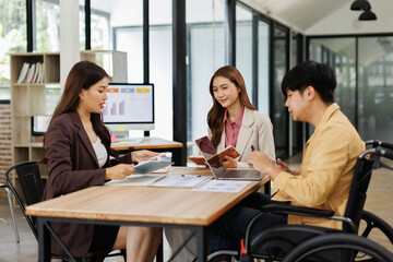 An inclusive modern office environment with a diverse team collaborating. A person in a wheelchair actively engages with colleagues.
