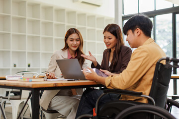 An inclusive modern office environment with a diverse team collaborating. A person in a wheelchair actively engages with colleagues.
