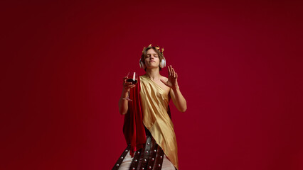 Fototapeta premium Man in toga and headphone listening to music with wine glass. Concept of ancient meets modern for social media, wine advertising, music campaigns, and lifestyle branding.